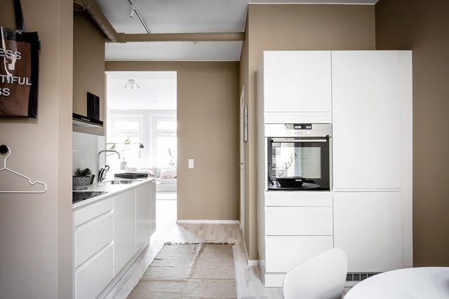 cucina bianca in contrasto con parete toni del marrone